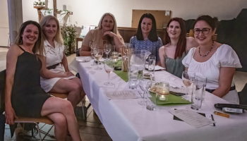 A group of women around a table smiling with glasses of wine
