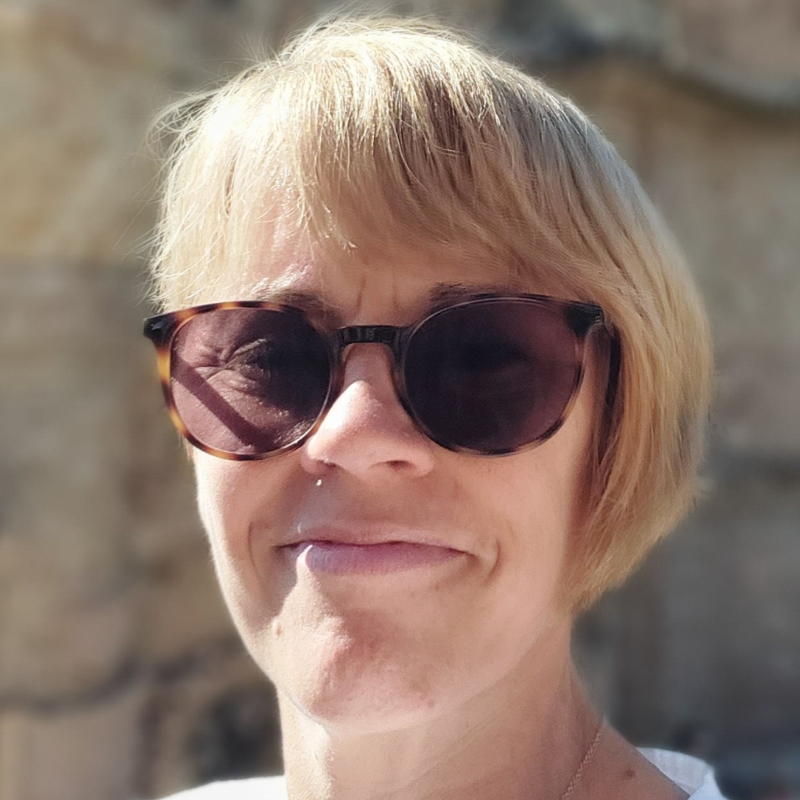 Beth Peal,  wearing sunglasses and smiling at the camera