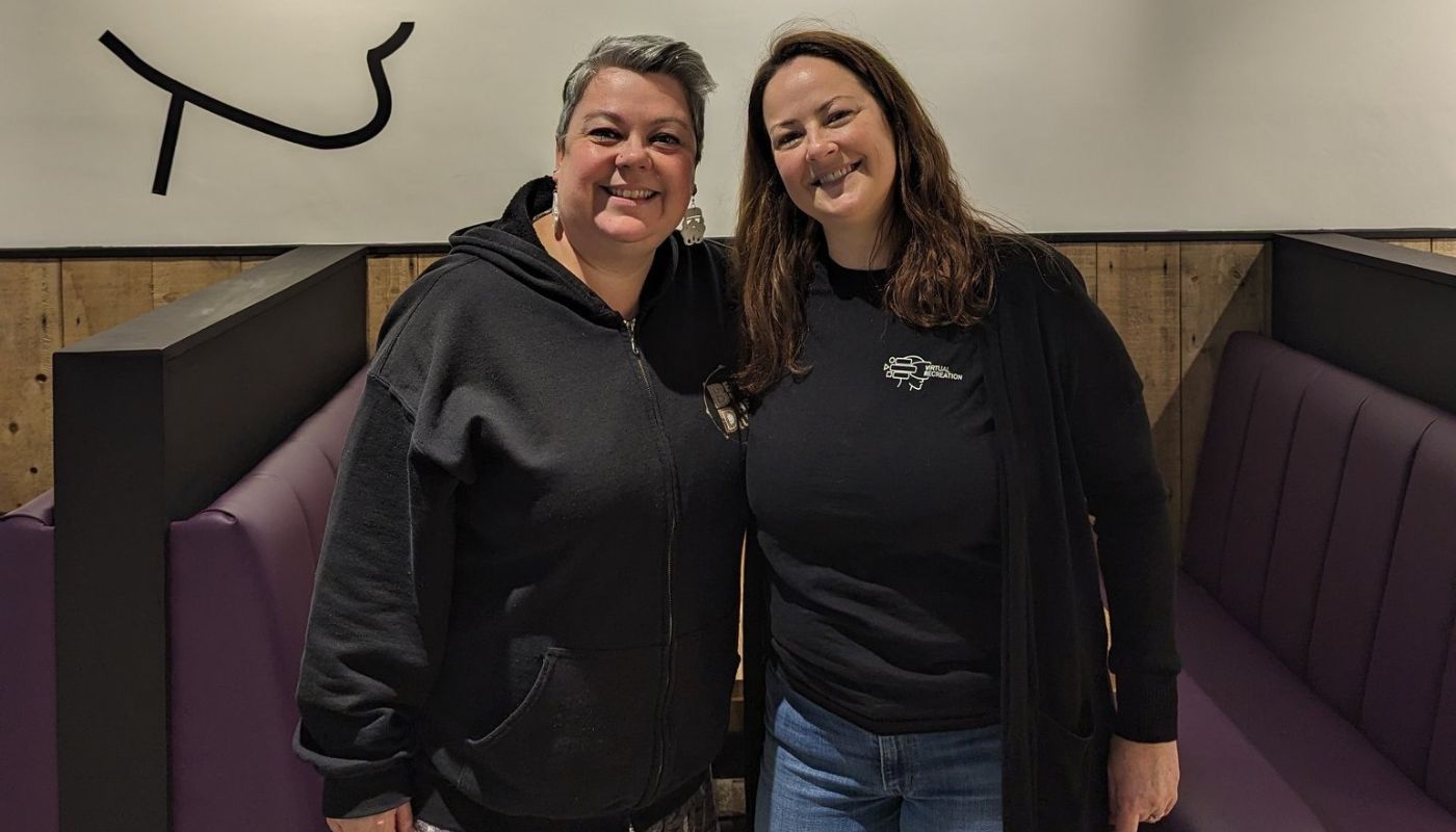 A photo of Jackie Dawes with her arm around a friend, smiling at the camera